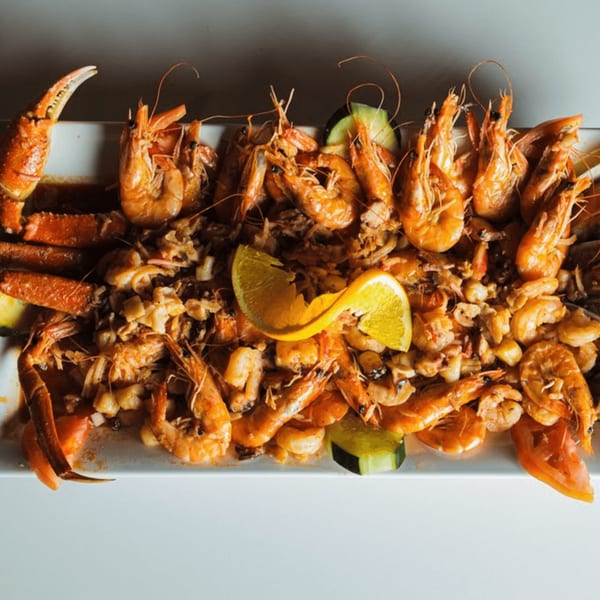 A large platter of Las Islas VIP seafood with shrimp, crab legs, and scallops, garnished with lemon and cucumber.