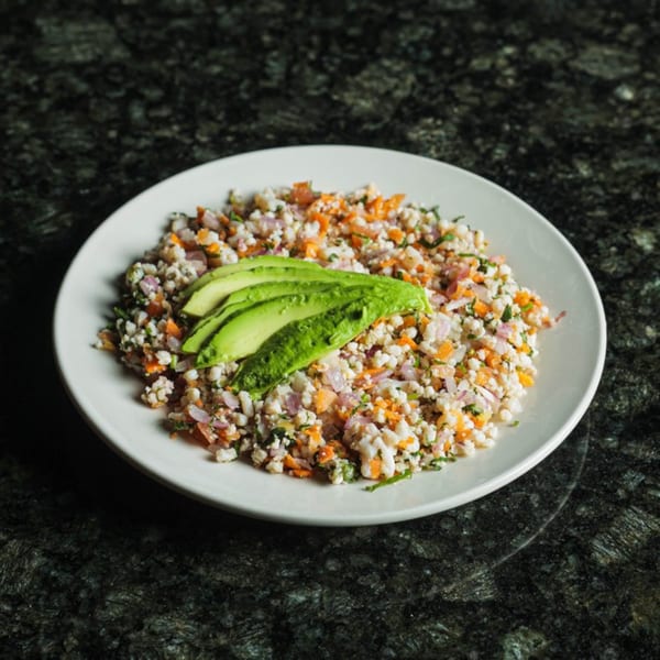 Seafood ceviche with diced red onion, carrots, and cilantro, topped with sliced avocado.